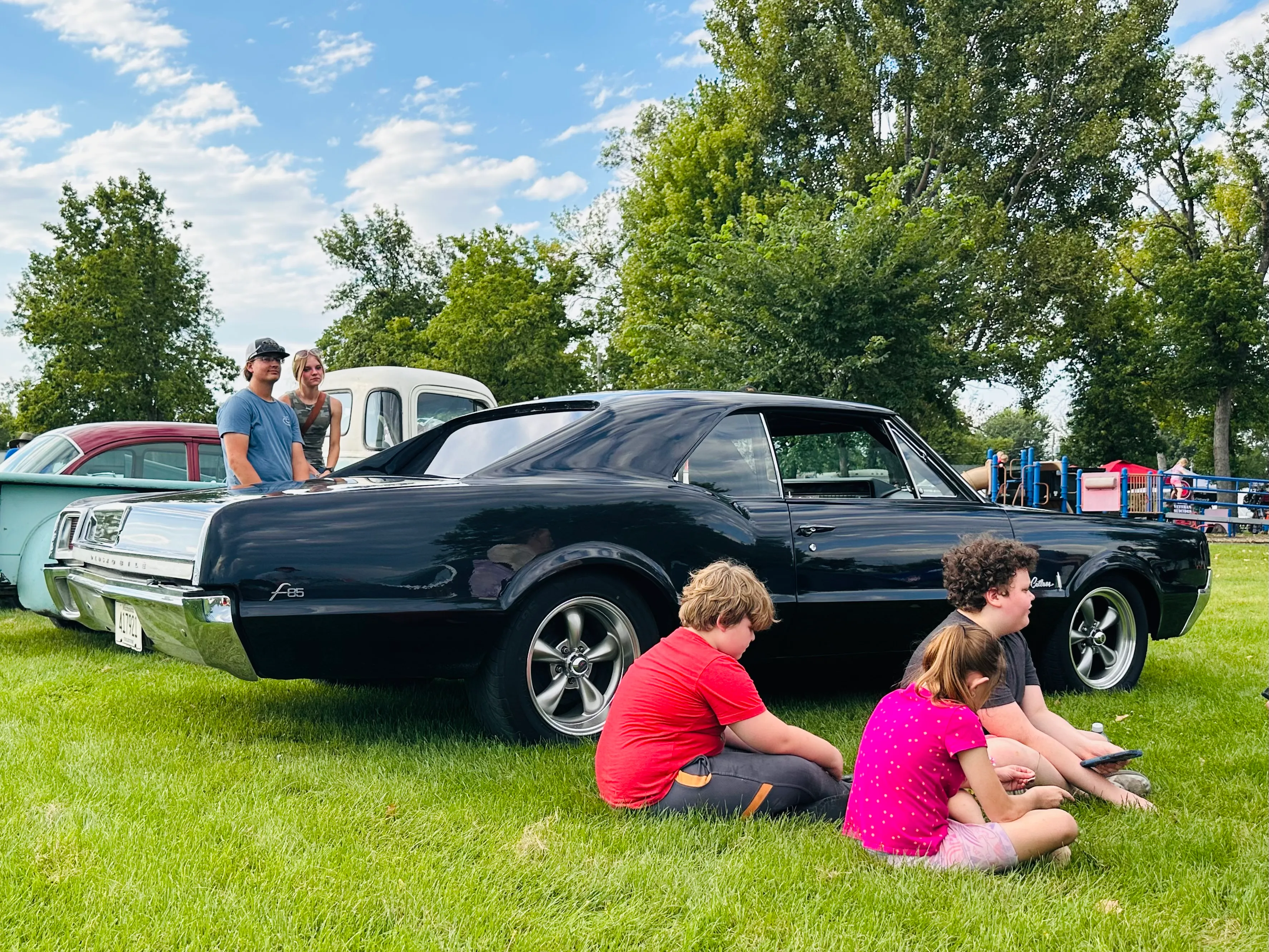 OK Tire staff member chatting with attendees next to a red and white vintage car