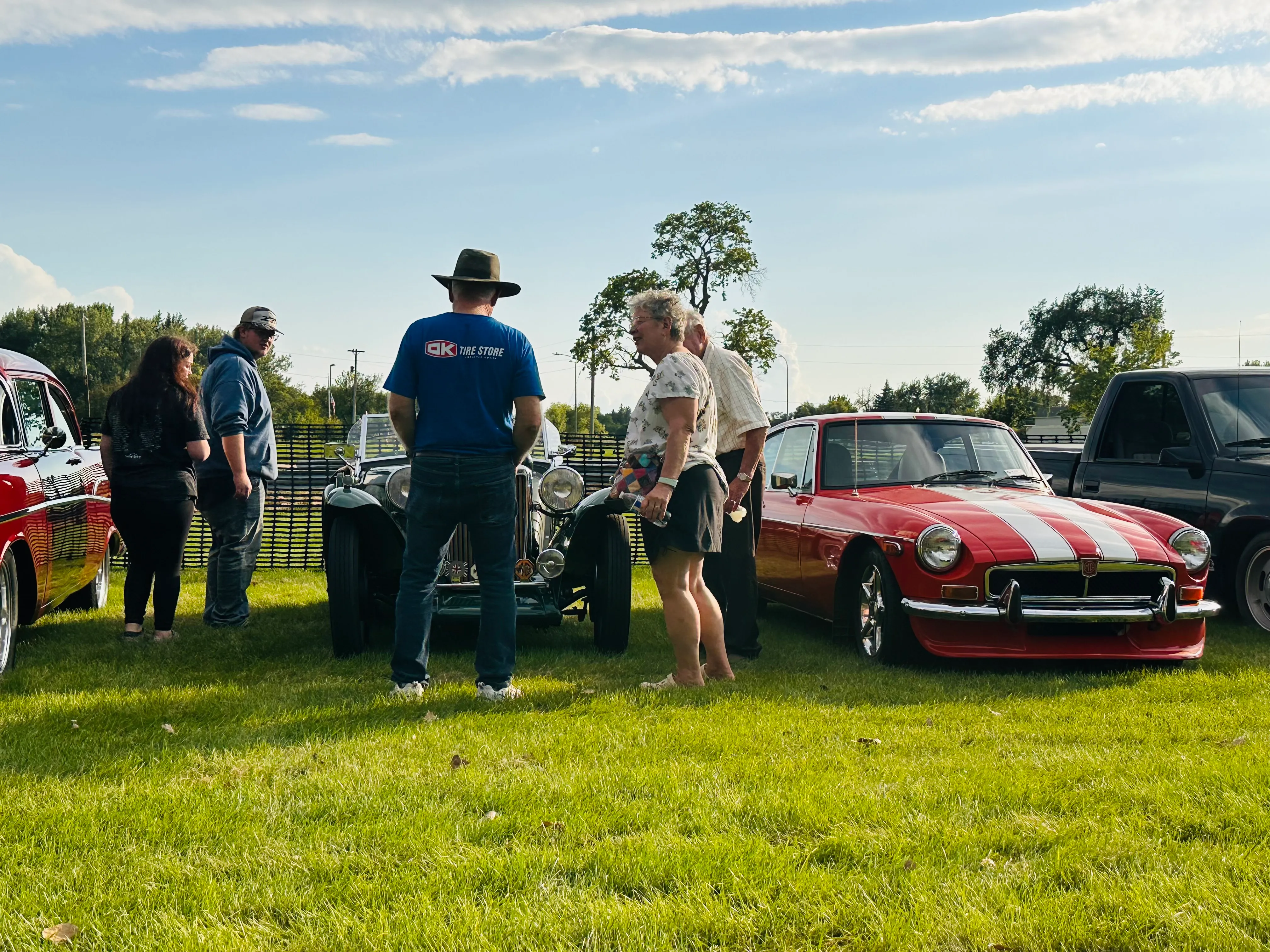 Bright yellow muscle car with hood open surrounded by event attendees