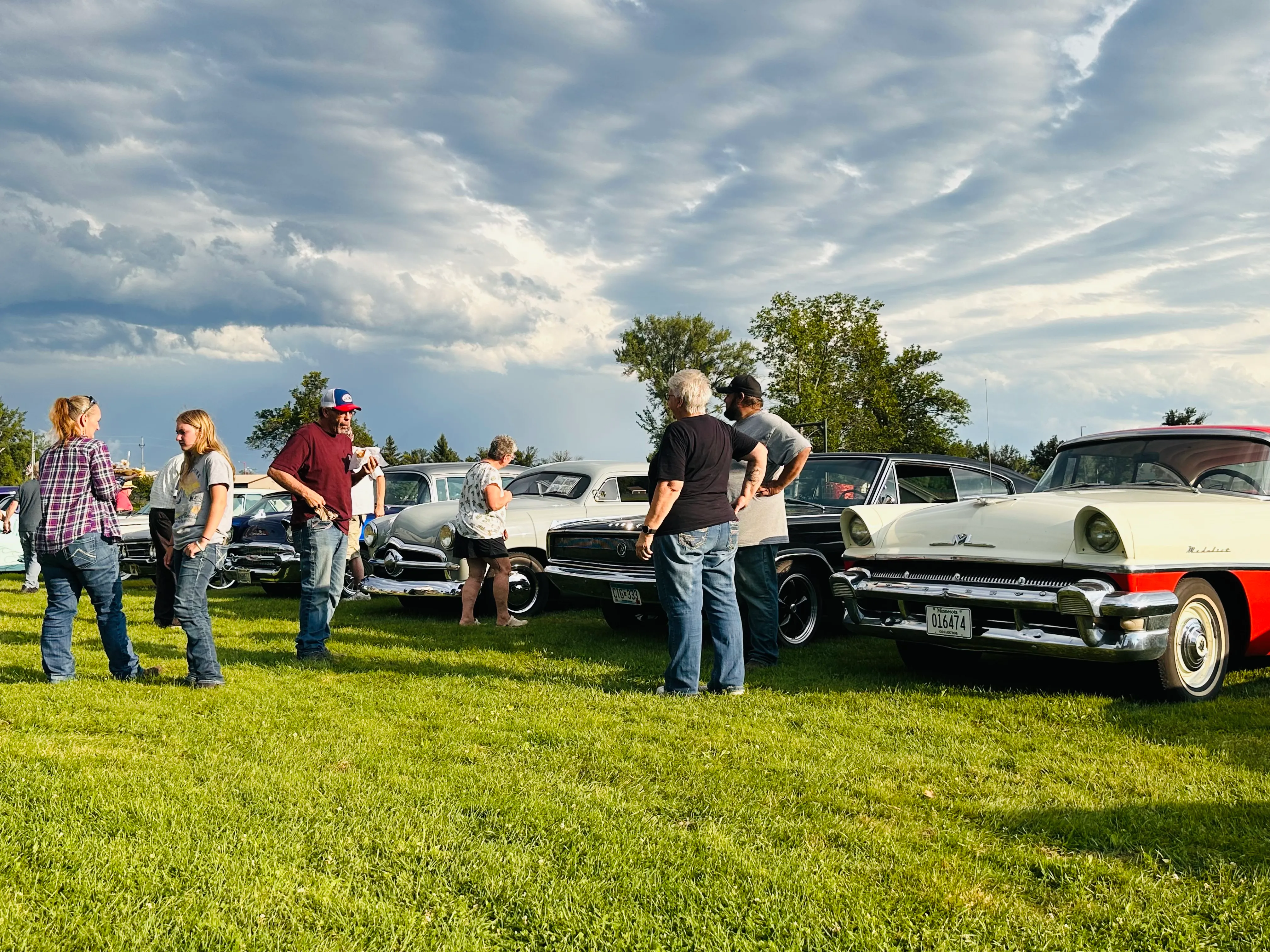 Light blue and purple custom cars displayed side by side with attendees examining them